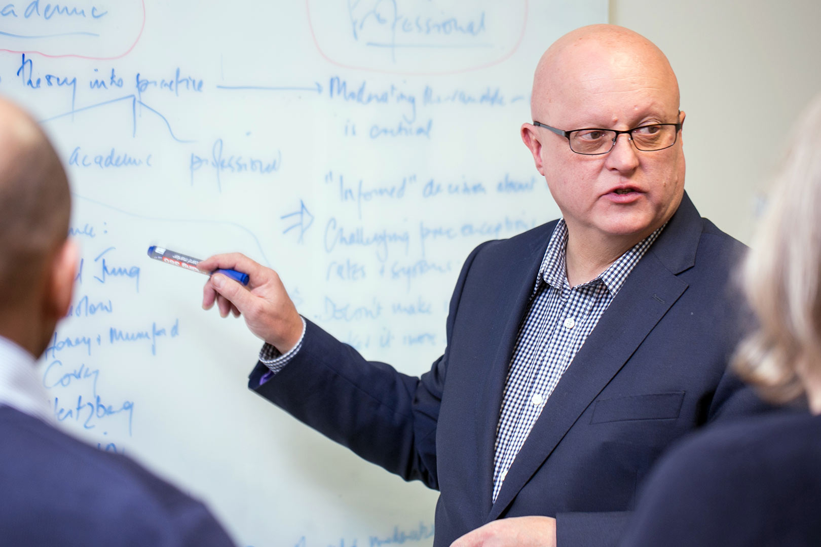 People having a meeting and making notes with a marker on a whiteboard