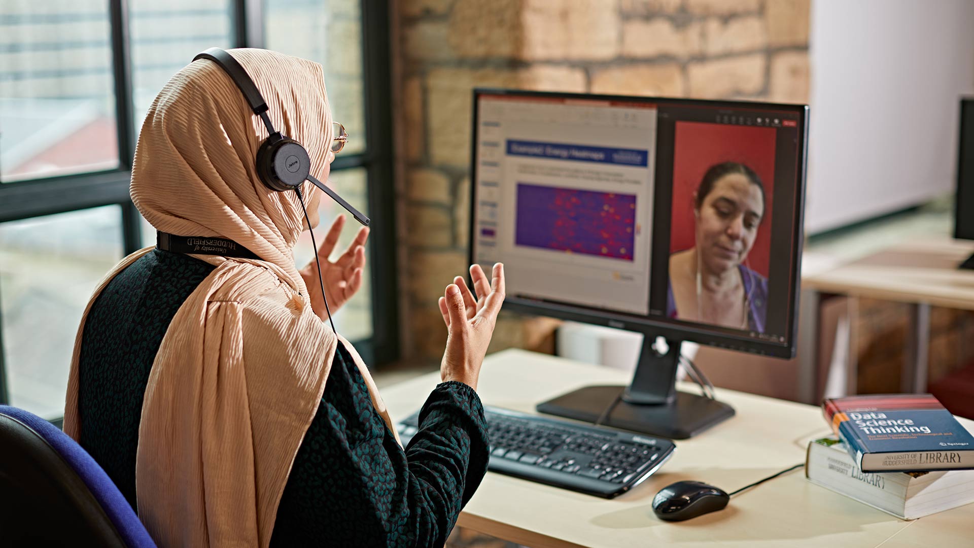 An academic delivering an online session to a student, visible on their computer screen.